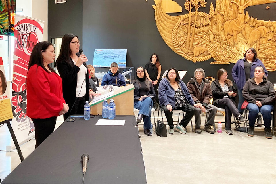 Chief Priscilla Mueller, with mic, of Saik’uz First Nation, speaks at a press conference calling for more action and resources to help find two young people missing from the community west of Prince George, while family members of the missing, other leaders, sit nearby. (Carrier Sekani Child & Family Services photo)