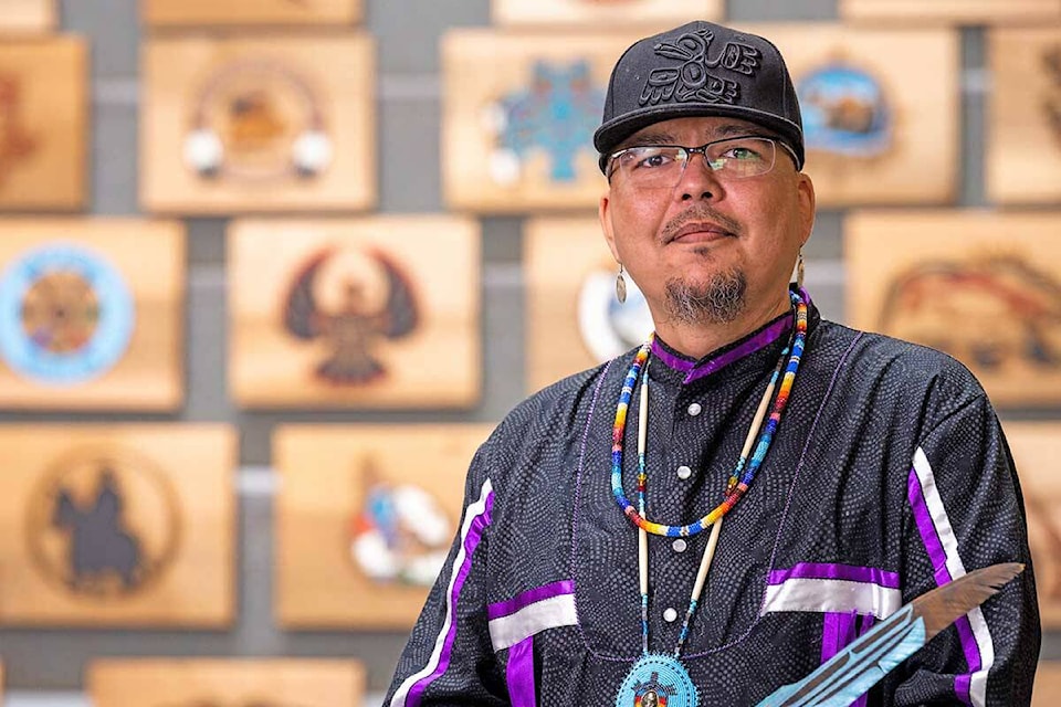 Cree Dakelh artist Clayton Gauthier stands in front of Nenachalhuya – The Cedar Plank. He had spent spent 18 months working on the project featuring the logos of 32 First Nations from across northern B.C. (UNBC photo)