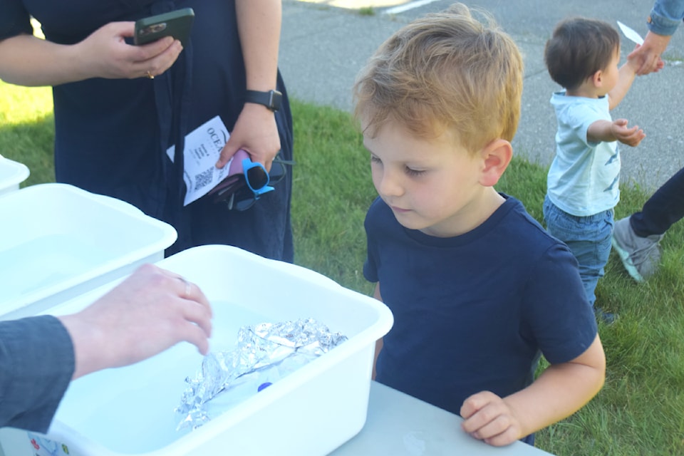 Lev Makortoff watches as marbles are added to a boat he made. Makortoff and other kids built boats as part of Sea School during Ocean Week on June 7. The goal was to build a model that could carry as many marbles as possible before sinking. 