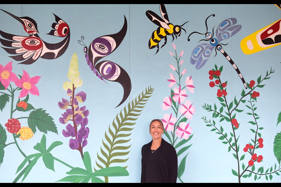 Jessica Chickite poses with her mural she painted for École Mer-et-montagne.