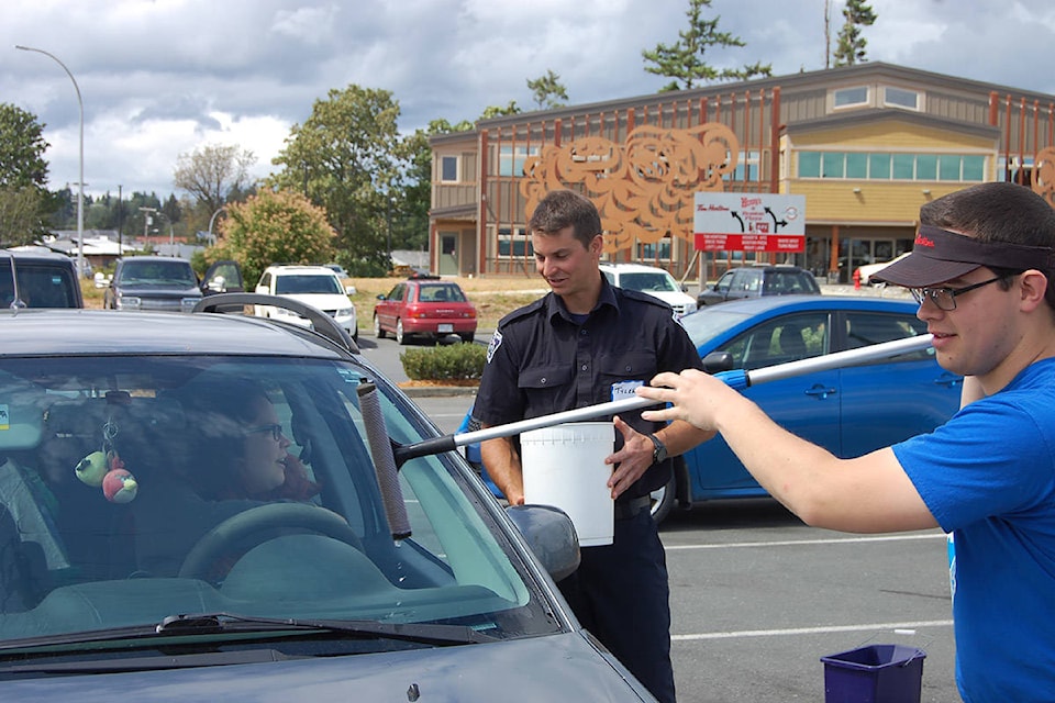 Firefighter Tyler Bruce is shown here accepting donations from a customer at the downtown Tim Hortons as part of Camp Day on June 6. Also pictured is Tim Hortons employee Tyler Araki, who washed windshields. Photo by David Gordon Koch/Campbell River Mirror