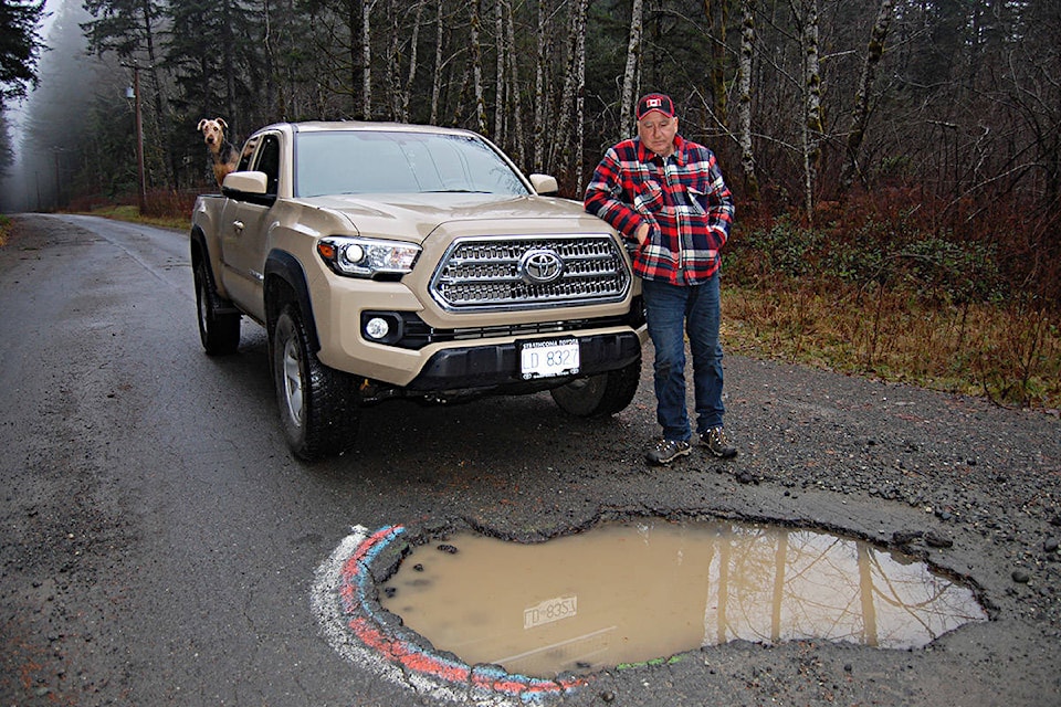 Area resident Duncan Devlin examines one of the massive potholes that drivers must swerve to avoid on Snowden Road, located north of the John Hart Dam. Photo by David Gordon Koch/Campbell River Mirror