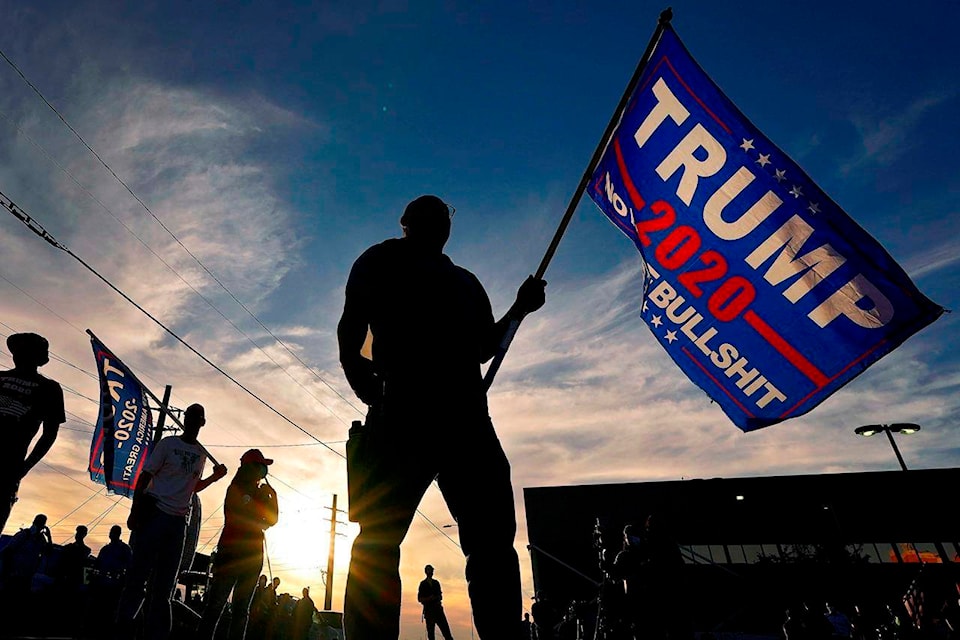 EDS NOTE: OBSCENITY - A Trump supporter stands outside the Maricopa County Recorder’s Office, where votes in the general election are being counted, Thursday, Nov. 5, 2020, in Phoenix. (AP Photo/Matt York)