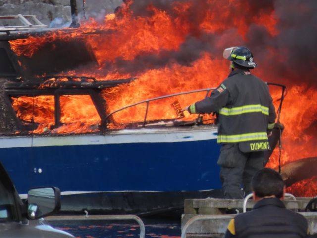 A firefighter works to extinguish one of the boats in Tuesday night’s fire. Photo supplied by NC via Facebook