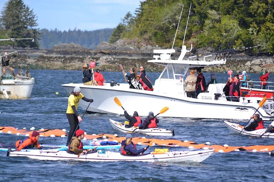 Vessels circle around a sign that reads ‘Fish Farms Out!’ during the May 7 Flotilla for Wild Salmon in the Tofino Harbour. (Nora O’Malley photo)