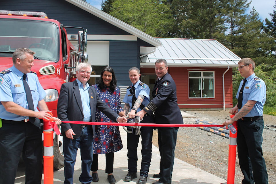 Merville Fire Rescue firefighters Graeme Sargent (left) and Chris Chambers hold the ribbon, while Edwin Grieve (CVRD Area C director), Arzeena Hamir (CVRD Area B director), Melisa Whitelaw (Merville Fire Rescue) and Bruce Green (Fire Chief, Oyster River Fire Rescue) perform the “cutting duties” at the official grand opening of the Merville fire hall. Photo supplied