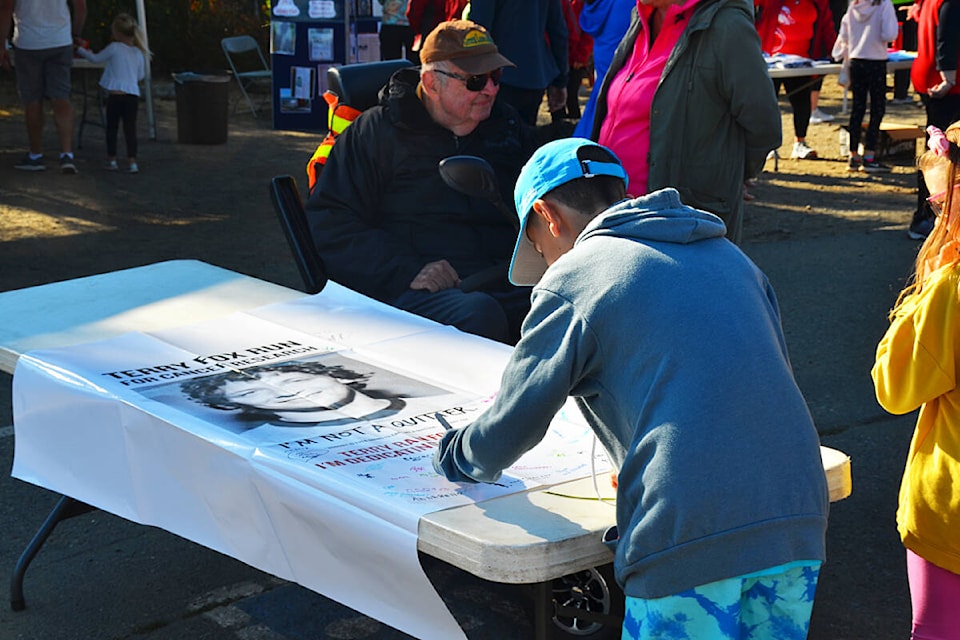 A young participant in Campbell River’s Terry Fox Run signs a poster of condolence at the run’s starting point at Frank James Park on Sunday, Sept. 18, 2022. Photo by Alistair Taylor/Campbell River Mirror