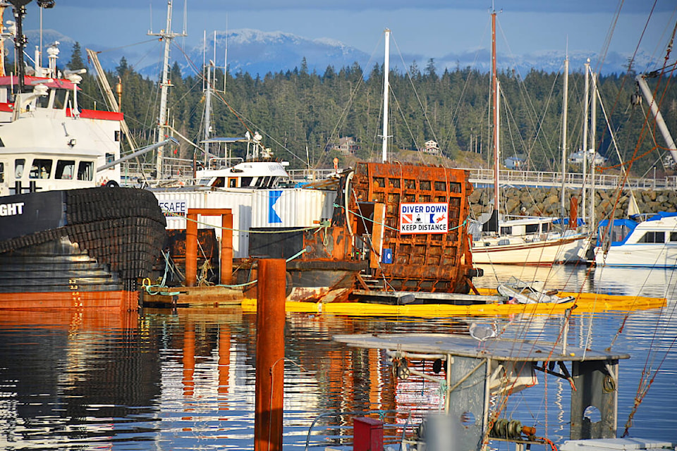 Containment boom marks site where two vessels sank in the early hours of Dec. 10, 2022 during a snowstorm while moored at a wharf finger at Campbell River Discovery Harbour Marina. Photo by Alistair Taylor/Campbell River Mirror