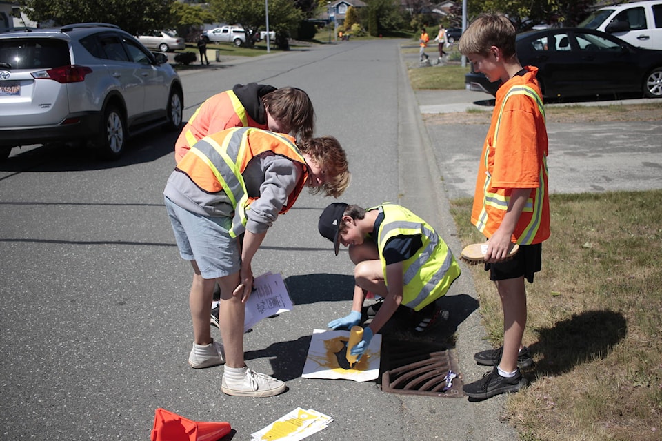 Students Fisher Saxby, Jackson Winspear, Matthew Bignell and Matthew Steele paint a yellow fish near a drain on Alexander Drive in Campbell River. The yellow fishes indicate to people that the drains lead to fish habitat, and that people should be mindful of what ends up in the drains. Photo by Marc Kitteringham/Campbell River Mirror