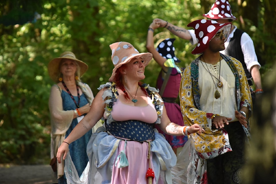 A troupe of performers dressed as mushrooms wander through the forest.