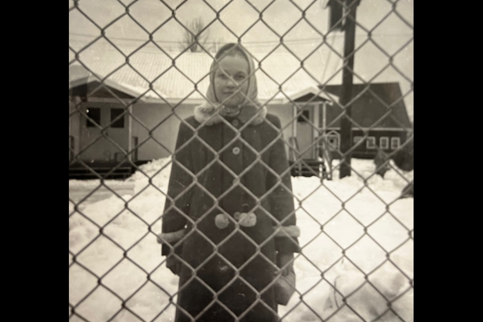 A girl poses for a photo behind the fence of the New Denver School in the mid-1950s.