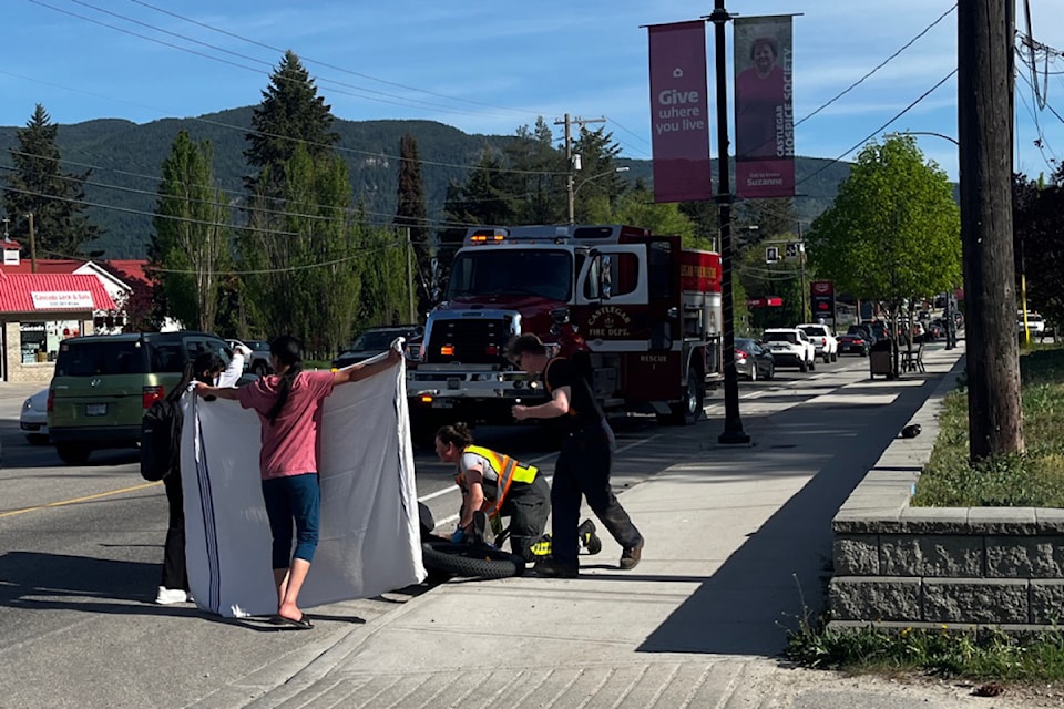 Onlookers hold up a blanket to provide privacy as emergency crews support the injured cyclist.