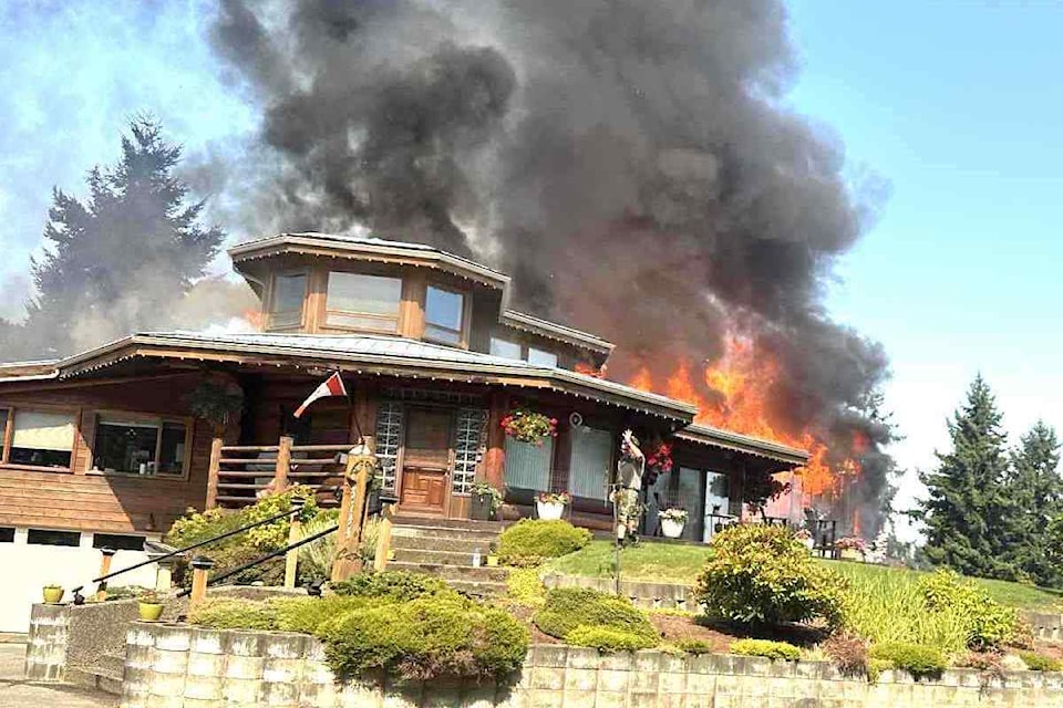 Flames and thick smoke pour from a home on Panorama Ridge in Chemainus on Aug. 25 as neighbours try to hold the fire at bay before crews arrived.