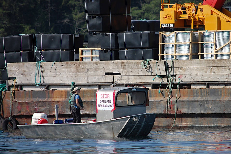 A protester in a small boat passes the Cyrus Rocks fish farm site in Okisollo Channel, northeast of Quadra Island, on May 28, 2019. Photo by David Gordon Koch/Campbell River Mirror