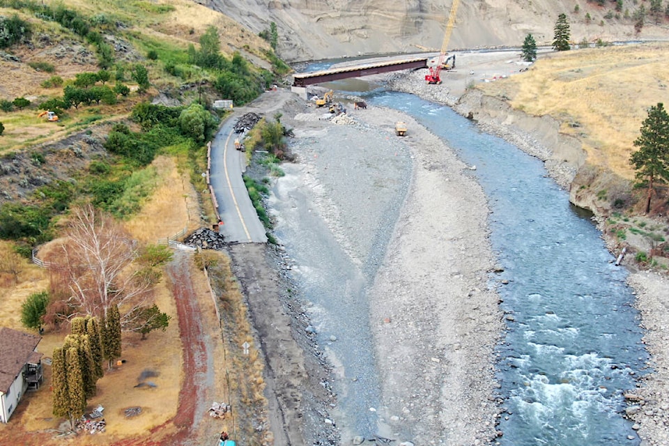 A temporary one-lane bridge being built across the Nicola River at IR7 near Osprey Ranch. The highway used to follow the base of the cliff, before the atmospheric river of November 2021. (Photo credit: Geoff Bannoff)
