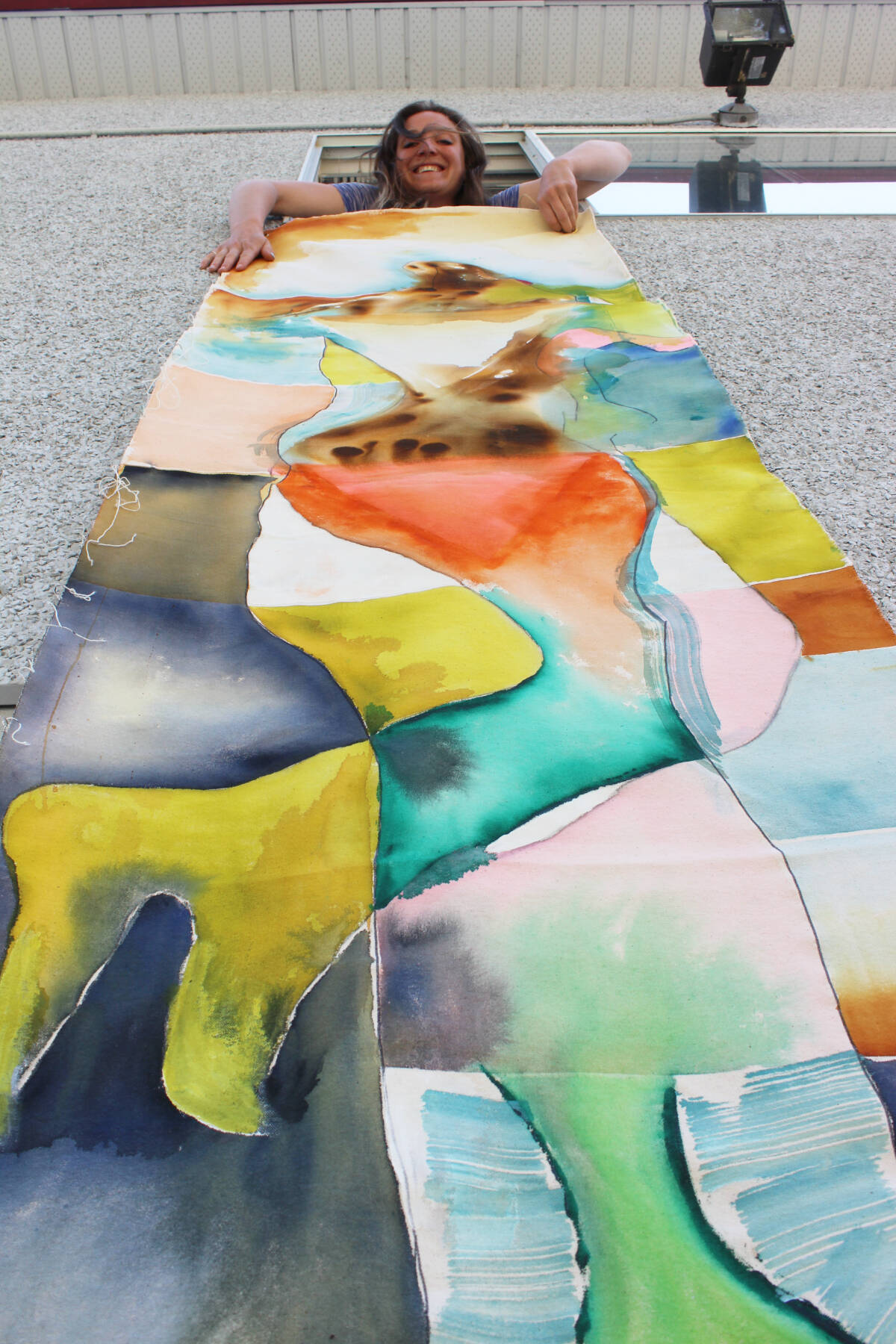 Skye Skagfeld unfurls another large-scale work from the window of the gallery. (Photo by Don Bodger)