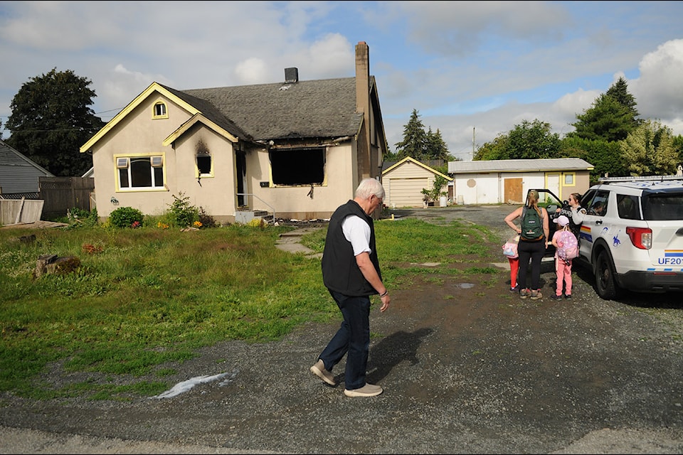 Neighbours chat with an RCMP officer following a fire at this vacant house on McNaught Road on Friday, June 28, 2024. (Jenna Hauck/ Chilliwack Progress)