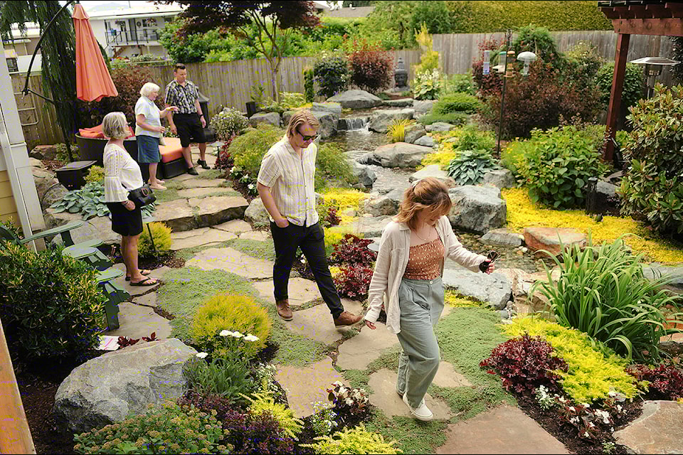 People admire a private garden at the home of Amber Price and David Short on Saturday, June 22, 2024. The home was one of eight stops on the annual Rotary Garden Tour. 