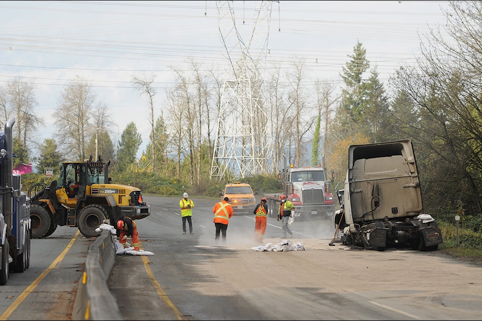 Crews clean up the mess left behind after this semi trailer tipped over and landed across Highway 1, east of Annis Road in Chilliwack, in an early-morning collision on Friday, Nov. 8, 2024. The cab of the truck is seen at the right.