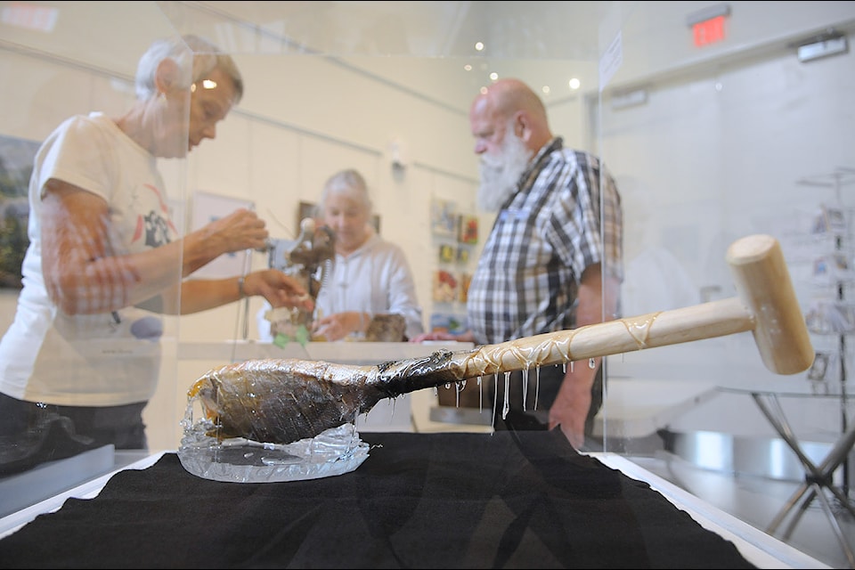 George Rychter (right) is seen by his art piece 'Fish Skin Oar' during the installation for group exhibition 'Canada, Eh?' by the Chilliwack Visual Artists Association on Sept. 17, 2024.