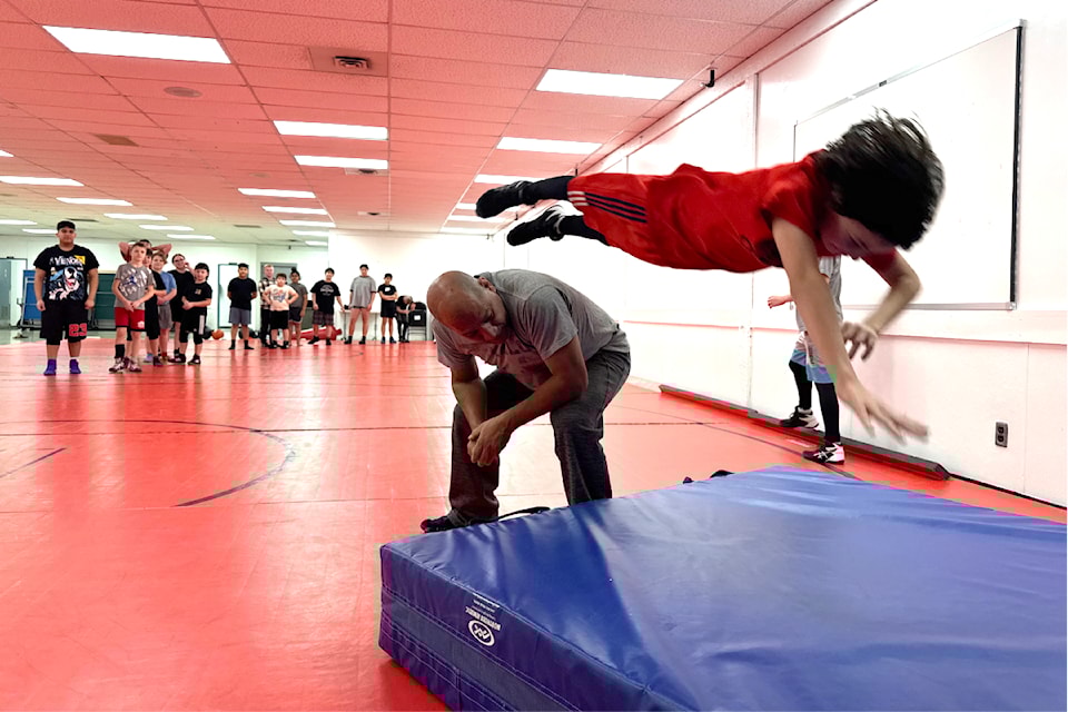 Wrestling coach Americo Pena leans over so members of the Chilliwack Grapplers Wrestling club can jump over him, at a practice on Jan. 15, 2025. 