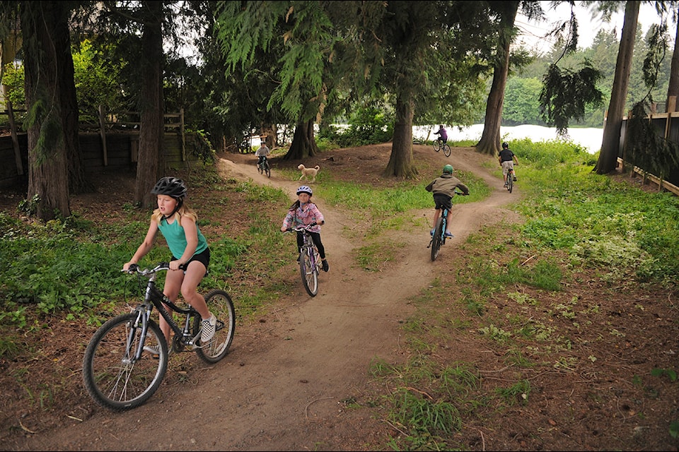Kids ride through a green space at 44692 Cumberland Ave. in Chilliwack on Tuesday, May 13, 2025. The lot, located on a residential street in between two houses, has been owned by the city for 34 years and is now up for sale.
