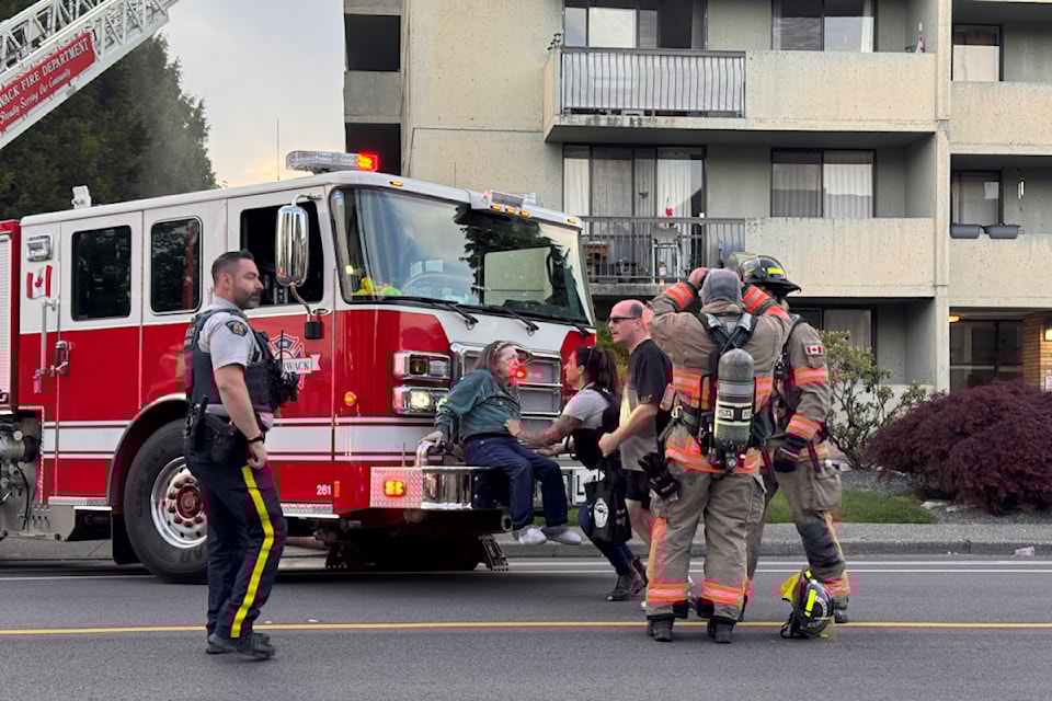 First responders help a resident with smoke inhalation on the bumper of a fire truck, during a fire at an apartment building on Mary Street in Chilliwack on May 6. 