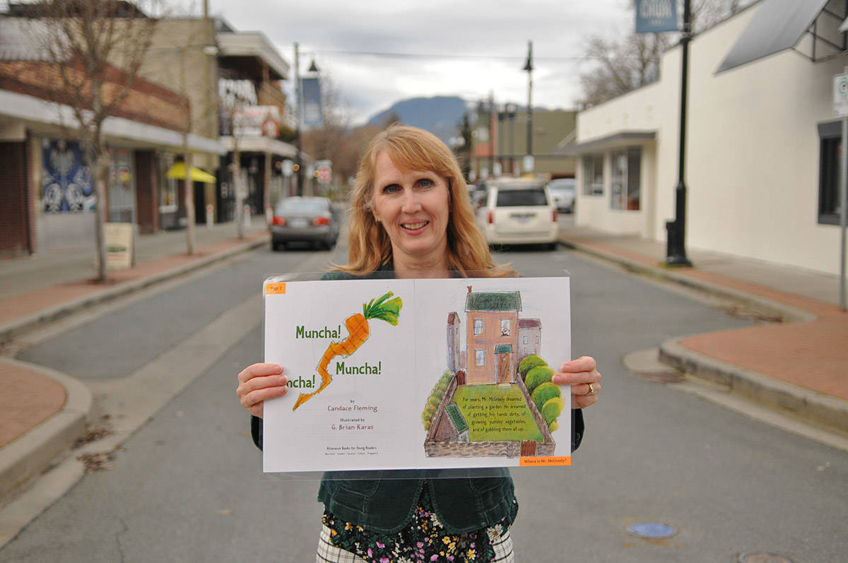 Annette Williams with Chilliwack Learning Society holds up one of the pages of Muncha! Muncha! Muncha! by Candace Fleming, the story chosen for the downtown StoryWalk event. (Jenna Hauck/ Chilliwack Progress)