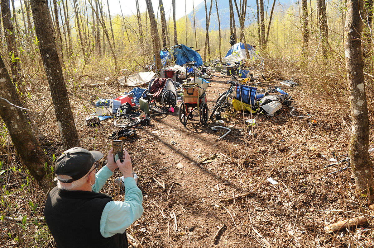 Terry Bodman snaps a photo on April 15, 2021 of one of the two active homeless camps he and other volunteers walked by during the 15-minute trek through a treed area of the Chilliwack River Valley to get to different homeless camp which caught fire on April 9. (Jenna Hauck/ Chilliwack Progress)