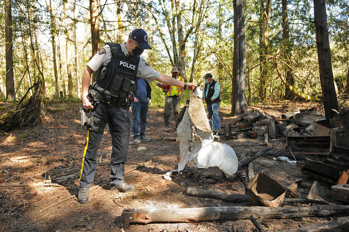 Const. Marc Verreault holds up a tarp likely used as part of a wall for the makeshift homeless structure which caught fire on April 9, 2021. (Jenna Hauck/ Chilliwack Progress)