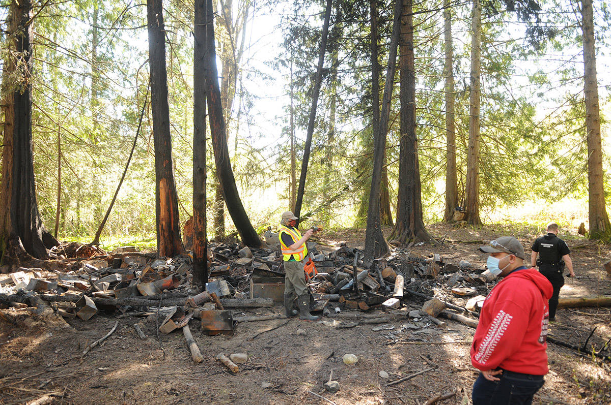 Volunteers, a conservation officer and an RCMP officer visit the burnt homeless camp on April 15, 2021. (Jenna Hauck/ Chilliwack Progress)