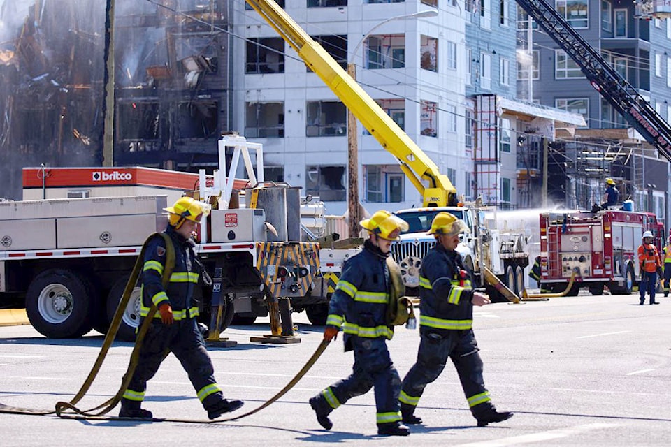 Firefighters carry equipment from the scene of Monday’s Willoughby fire. The April 19, 2021 blaze turned the Alexander Square development at the corner of 208th Street and 80th Avenue to rubble. (Rob Wilton/Special to Langley Advance Times)