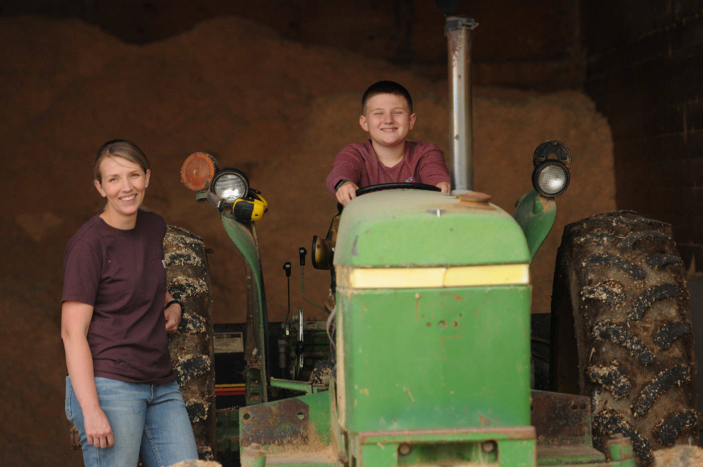 Winston Sache, 11, sits in a tractor beside mom Sarah at their home, West River Farm, in Chilliwack on Tuesday, June 15, 2021. (Jenna Hauck/ Chilliwack Progress)