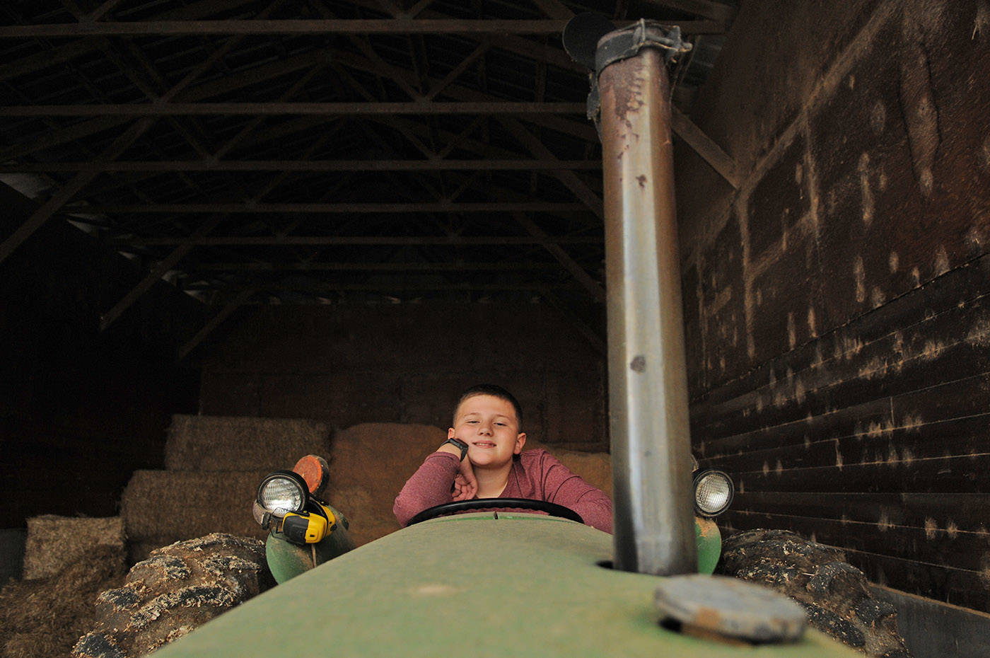 Winston Sache, 11, sits in a tractor at his home, West River Farm, in Chilliwack on Tuesday, June 15, 2021. (Jenna Hauck/ Chilliwack Progress)