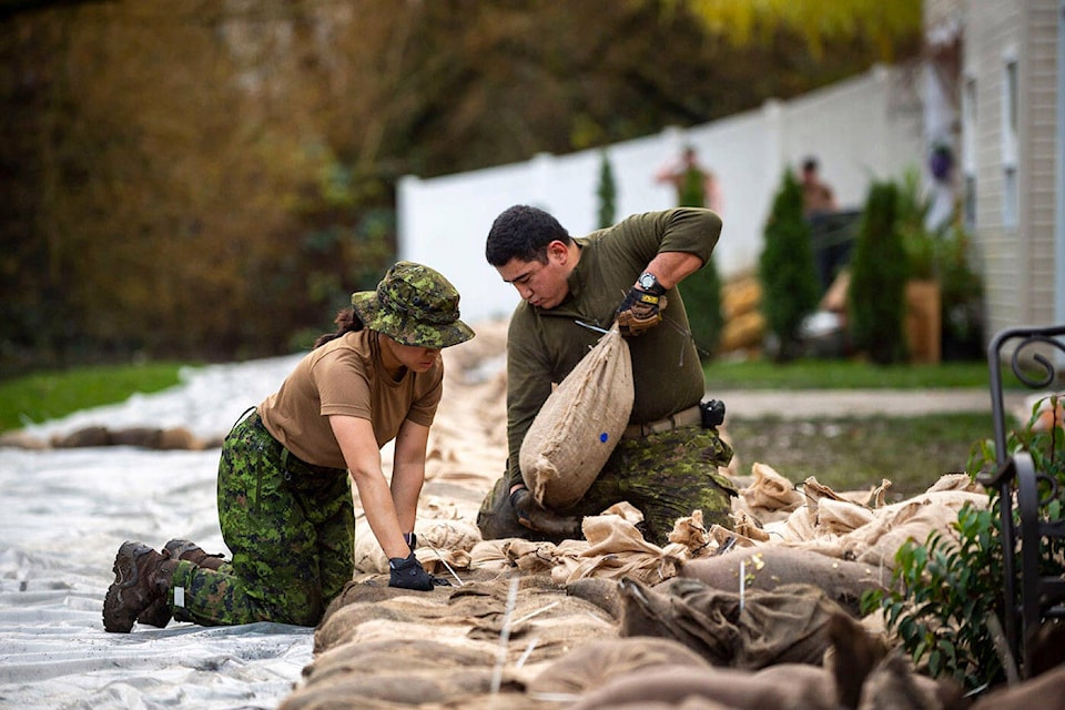 Bombardier Alina Liang from 5th (British Columbia) Field Artillery Regiment and Master Bombardier Joseph Rozario from 15th Field Artillery Regiment build a sandbag wall behind residential homes in order to protect them against potential flooding in Chilliwack, British Columbia on 29 November 2021. (MCpl Nicolas Alonso, Canadian Forces Combat Camera, Canadian Armed Forces Photo)