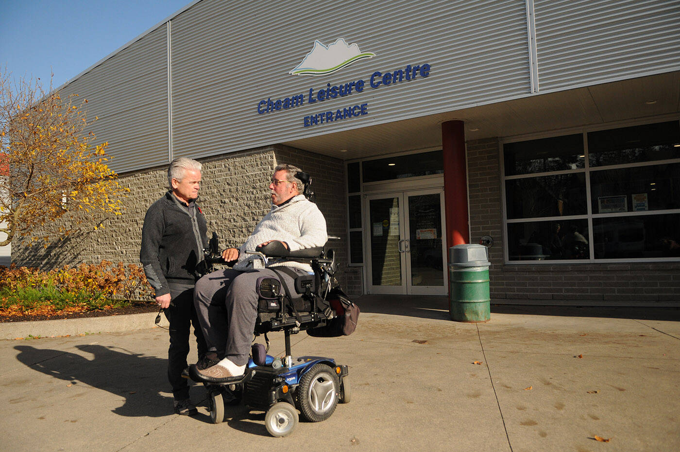 Jim Ryan (right) and Mayor Ken Popove chat outside the Cheam Leisure Centre before a tour of the building on Wednesday, Nov. 10, 2021. Ryan was pointing out some of the features at the centre that earned it the Rick Hansen Foundation Accessibility Certified Gold rating. (Jenna Hauck/ Chilliwack Progress)