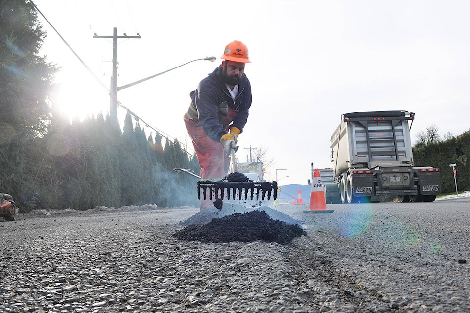 Shane Bellavance with the City of Chilliwack public works department repairs potholes along Chilliwack Mountain Road on Friday, Jan. 14, 2022. (Jenna Hauck/ Chilliwack Progress)