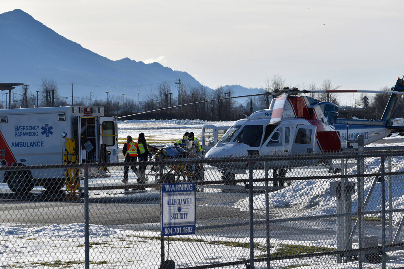 A man is transferred from an ambulance to a helicopter at the Chilliwack Airport following a collision on Young Road where a dump truck went into a ditch under the Highway 1 overpass on Friday, Jan. 14, 2022. (Mace MacGowan)
