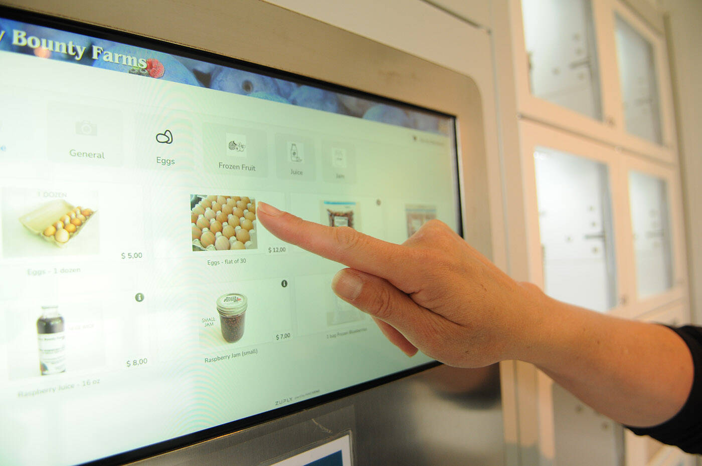 The vending machines at Berry Bounty Farms holds room-temperature, refrigerated and frozen items. Here, Leanne Maljaars shows how to use the machine. (Jenna Hauck/ Chilliwack Progress)