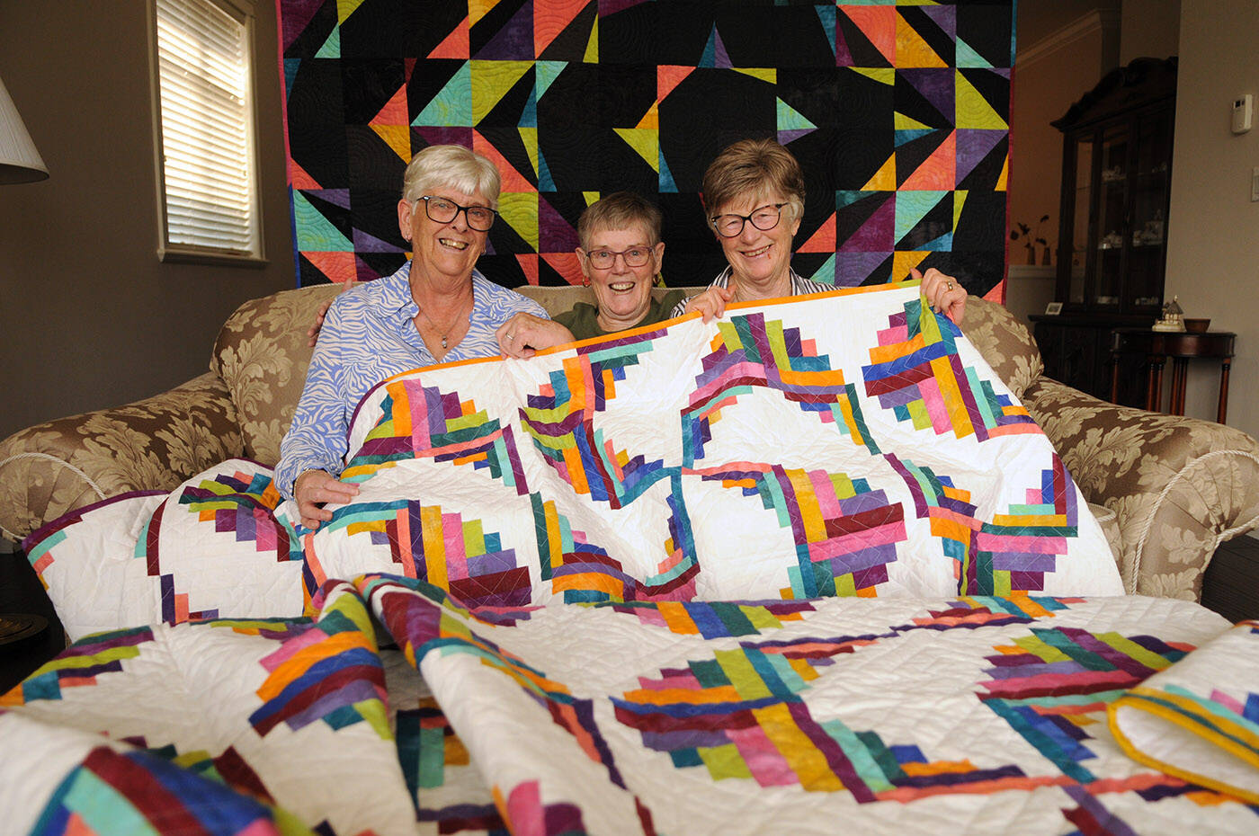 From left, Janet Skulsky, Sandra Lounsbury and Lyn Robinson show off the two quilts that will be raffled off at the Chilliwack PieceMakers Quilt Guilds 2022 Piecemaking in the Valley show. (Jenna Hauck/ Chilliwack Progress)