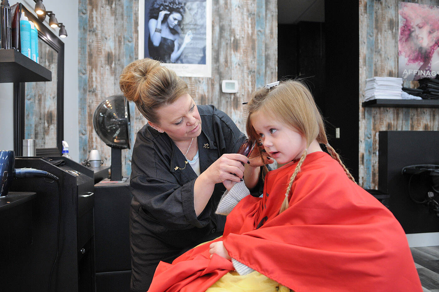 Three-year-old Kairi Ketler holds the clippers as Brenda Miller gives Kairi her first haircut at Sassy Cuts on Friday, Dec. 16, 2022. Kairi is donating her 12-inch ponytails to be made into wigs for kids, and is also fundraising for charity. (Jenna Hauck/ Chilliwack Progess)