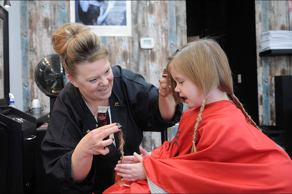 Brenda Miller gives three-year-old Kairi Ketler her first haircut at Sassy Cuts on Friday, Dec. 16, 2022. Kairi is donating her 12-inch ponytails to be made into wigs for kids, and is also fundraising for charity. (Jenna Hauck/ Chilliwack Progess)
