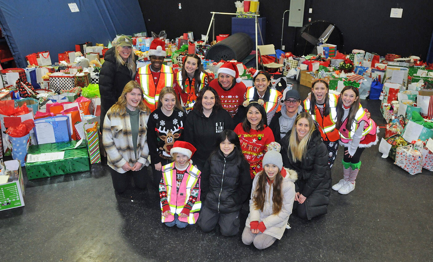Volunteers pose for a photo in front of just some of the 1,100 gifts donated as part of the third annual Adopt-A-Senior program on Saturday, Dec. 17, 2022. (Jenna Hauck/ Chilliwack Progress)