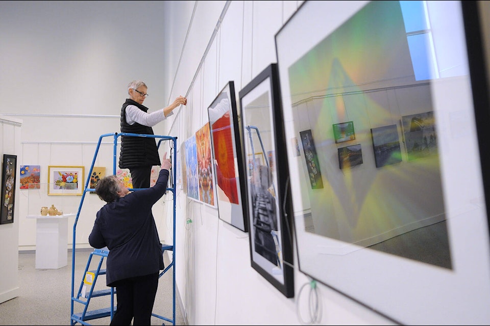 Chilliwack Visual Artists Association members Christine Newsome and Mary-Lee Merz help hang artwork on the walls for group show Inspire at the Chilliwack Cultural Centre on Tuesday, March 28, 2023. (Jenna Hauck/ Chilliwack Progress)