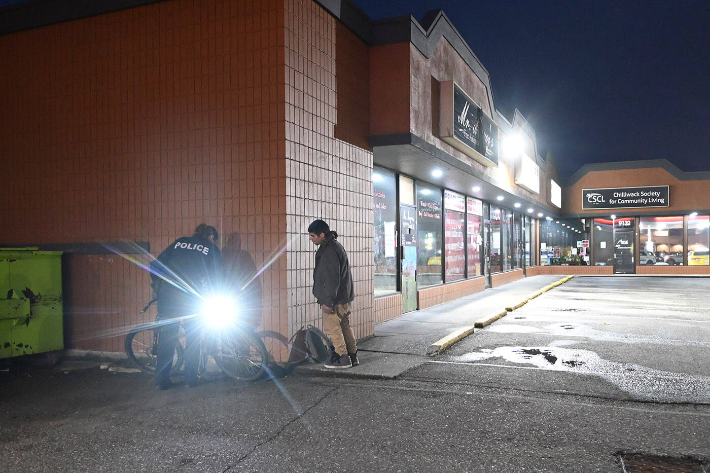 Chilliwack RCMP Sgt. Krista Vrolyk uses a flashlight to check the serial number of a bicycle before sending a young man on his way with his bike on Friday, May 5, 2023. (Jenna Hauck/ Chilliwack Progress)