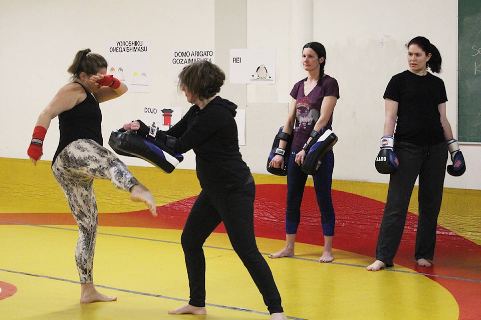 Kickboxing instructor, Sonya Dowker, demonstrates how to do a kick on Myrna Harrod-Taniguti while Jen Belle and Amber Benoit observe during a Mom’s Fight Club session at Clearwater Secondary School on Feb. 24. Photo by Jaime Polmateer
