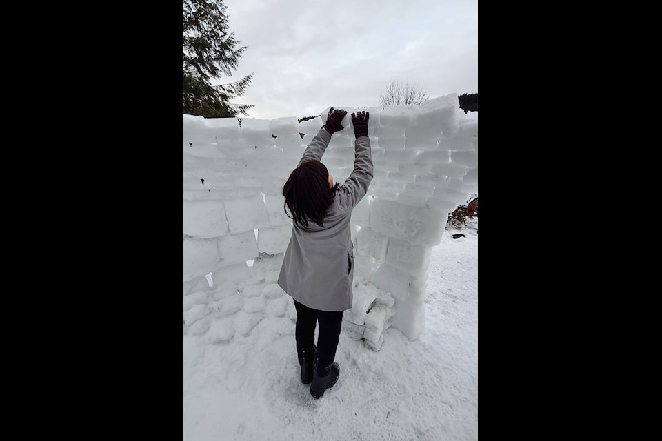 Michelle Tsao adds block of snow to the igloo to start forming the dome roof. The blocks are fused together by spritzing them with water from a spray bottle.