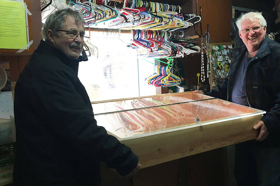 Chuck Neathway and Ron Colbourne install the new display case, which thrift store volunteers thank the Men’s Shed for with a donation and a promise of baking. (Photo: Mary Neathway).