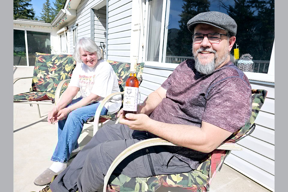 (From L - R): Shirley Wiley and Kenton Moore on the deck of their home at Wiley's Buzz Farm showing a bottle of Bone Hill Mead home recipe on April 25 during an interview with the Barriere Star/Journal. 