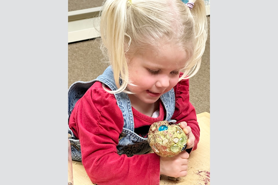 Lydia Andrews seems fascinated by her creative dragon egg while attending the Barriere Library Craft Day on Wednesday March 26. 